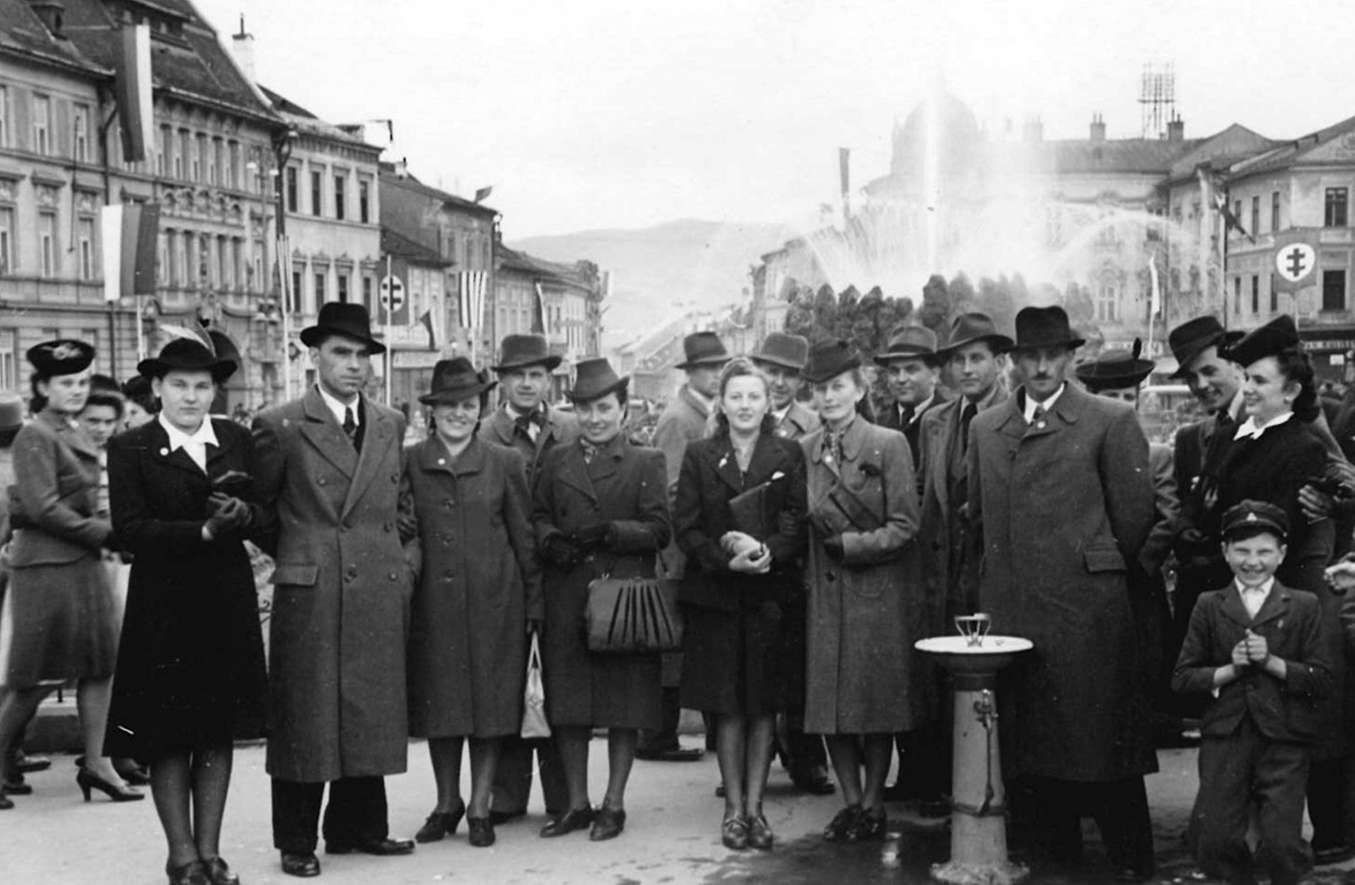 A large group poses in a town square, capturing a moment from family history and migration.